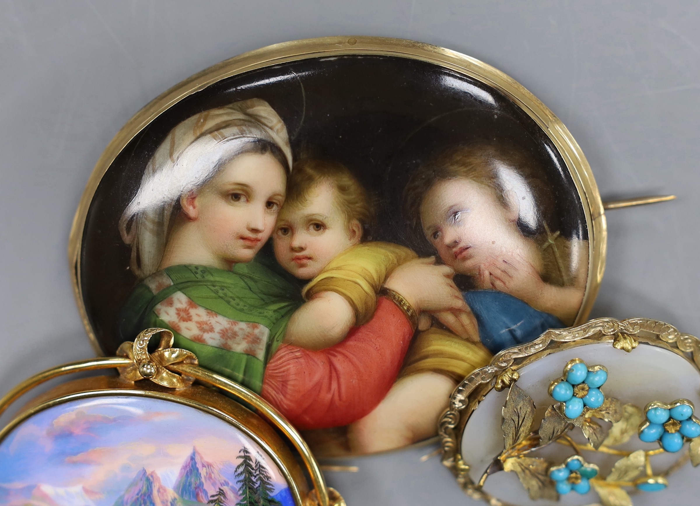 A Victorian 15ct gold mounted porcelain plaque, decorated with the Madonna della Sedia, 8cm, a Swiss landscape enamel brooch with 15ct mount, 6.5cm and a Pinchbeck brooch with turquoise set foliate decoration